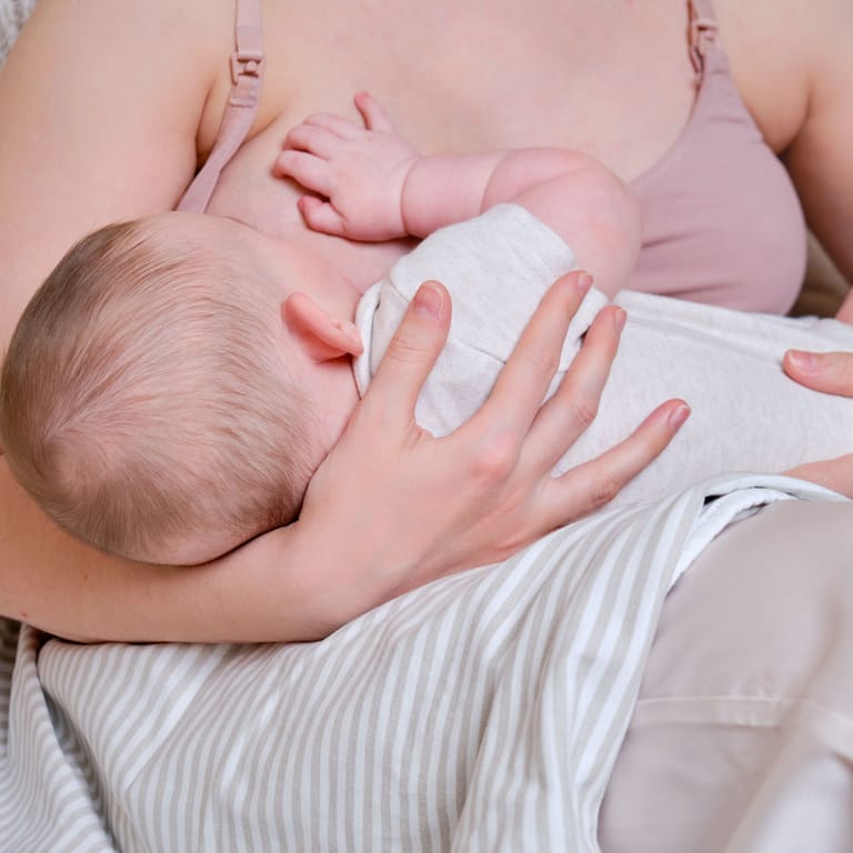 Mum and baby breastfeeding - shows baby's head at the breast. A lactation consultant can help you position baby better at the breast.